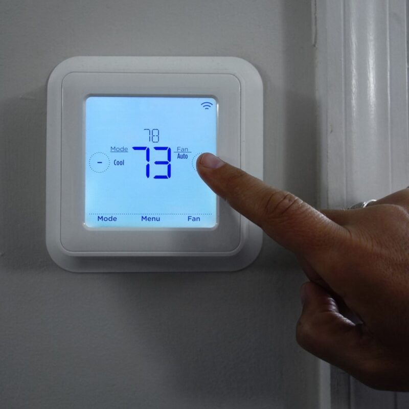 Rising Electric Bills in Tampa: How Your AC System Affects Costs and What You Can Do, A person adjusting the thermostat