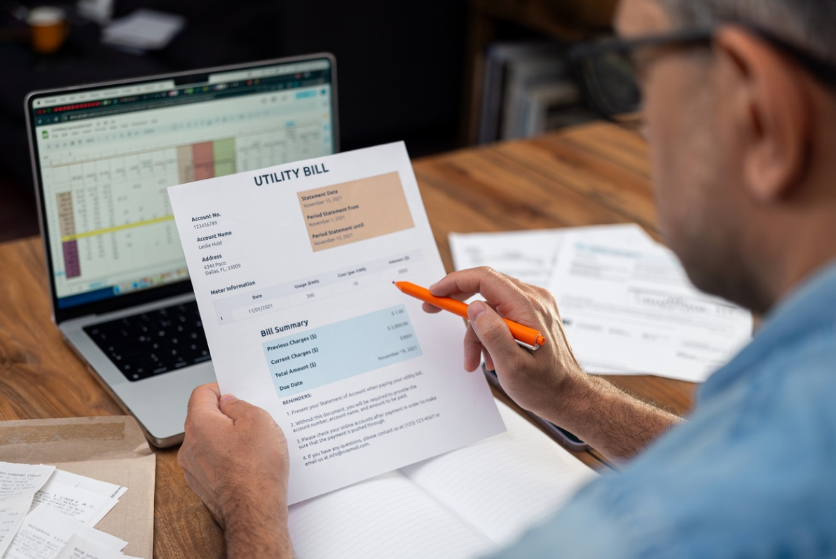 Homeowner reviewing a high utility bill at a desk, illustrating rising energy costs caused by an inefficient air conditioning system.
